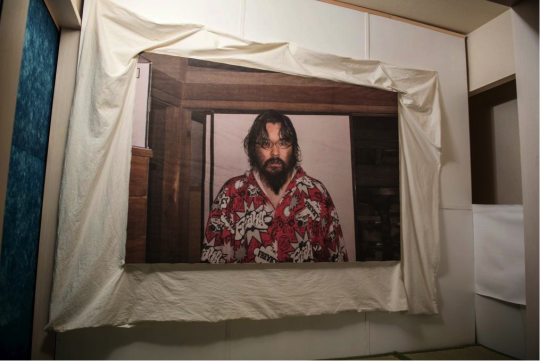 ひきこもりを止めた日に撮った写真。個展では、当時の布団カバーを再現したものに印刷して展示されていた。 自画像（布団カバー） / ©ATSUSHI WATANABE photo:Keisuke Inoue 